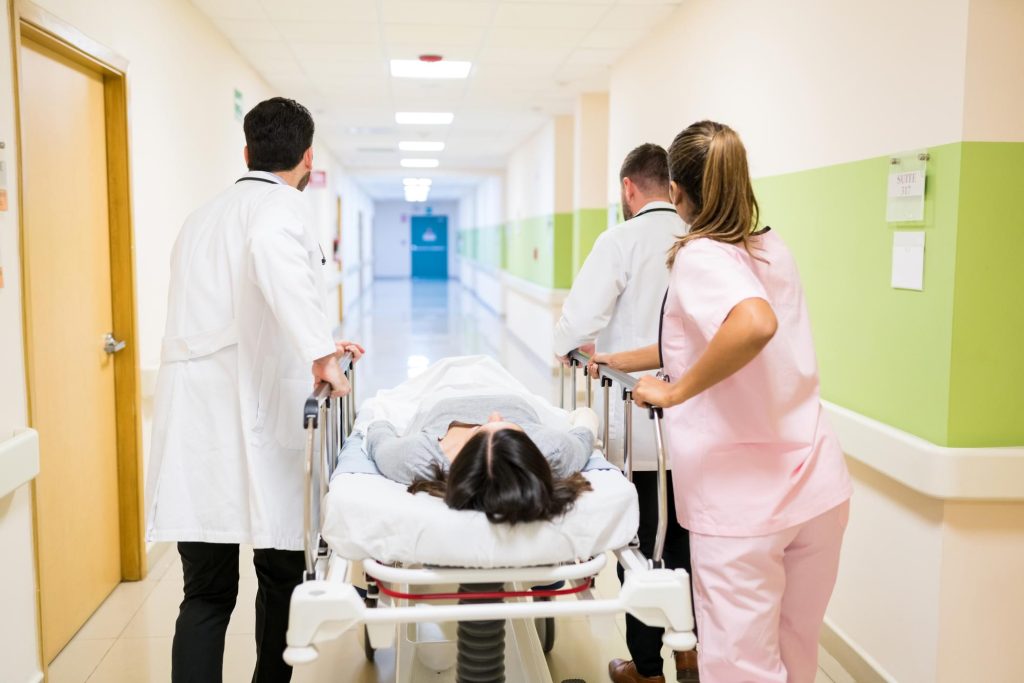 doctors nurse pushing female patient stretcher corridor hospital